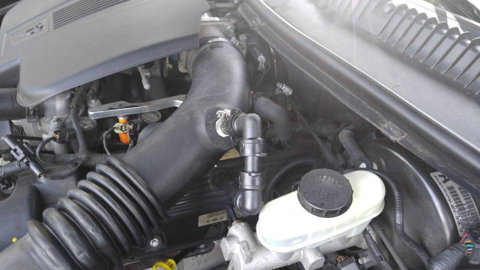 Engine bay of a 2004 Lincoln Town Car, showing air intake hose and brake fluid reservoir.