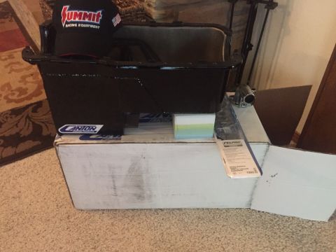 1982 Ford Bronco - A black Canton oil pan sits atop a white cardboard box. A black Summit Racing Equipment hat is placed on the edge of the oil pan.
