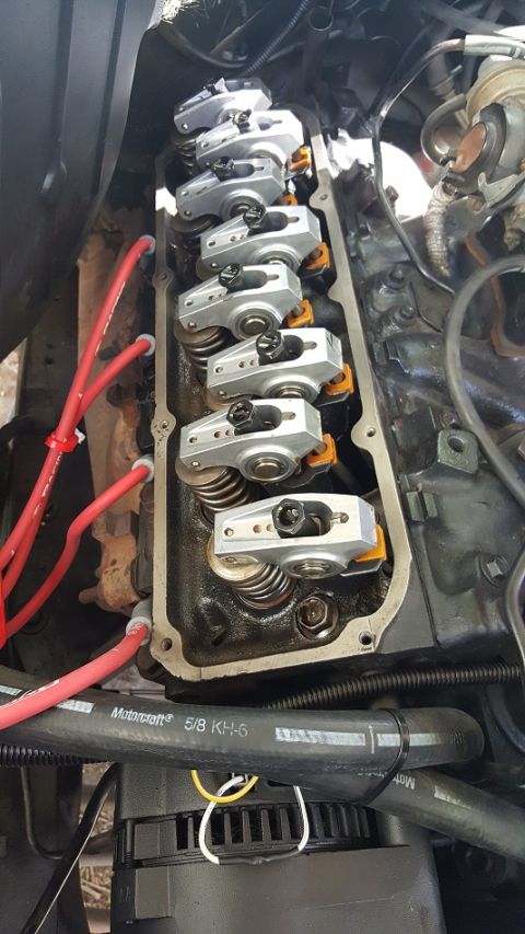 1978 Ford Bronco - A close-up view of the valve train on a Ford V8 engine, showing rocker arms and valve springs. Red spark plug wires are visible above the e…