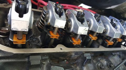 1978 Ford Bronco - A close-up view of the valve train components of a V8 engine. The image shows rocker arms, valve springs, and pushrods, with orange plastic…