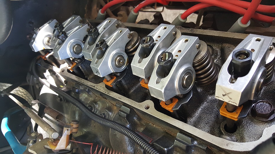 Close-up of V8 engine rocker arms and valve springs, with orange retainers.