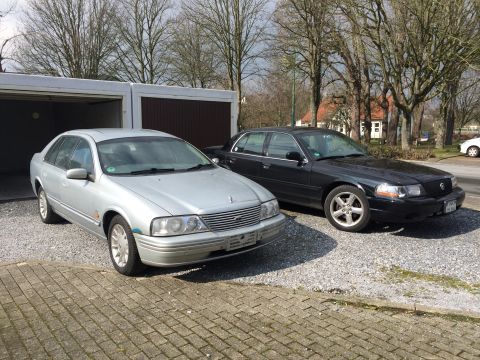 1999 Ford Fairlane - A silver 1999 Ford Fairlane sedan is parked in front of a garage. Next to it is a black sedan.