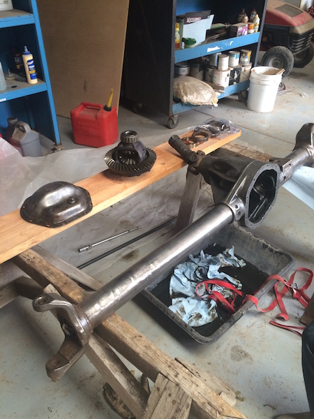 1981 Ford Bronco - A disassembled rear axle assembly is laid out on sawhorses in a garage or workshop setting. Visible parts include the differential housing,…
