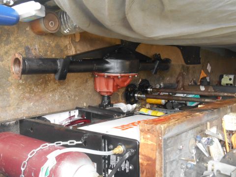 1972 Ford Bronco - A black rear axle assembly with a red differential housing is mounted on a workbench. Two axle shafts are laid out in front of the assembly…