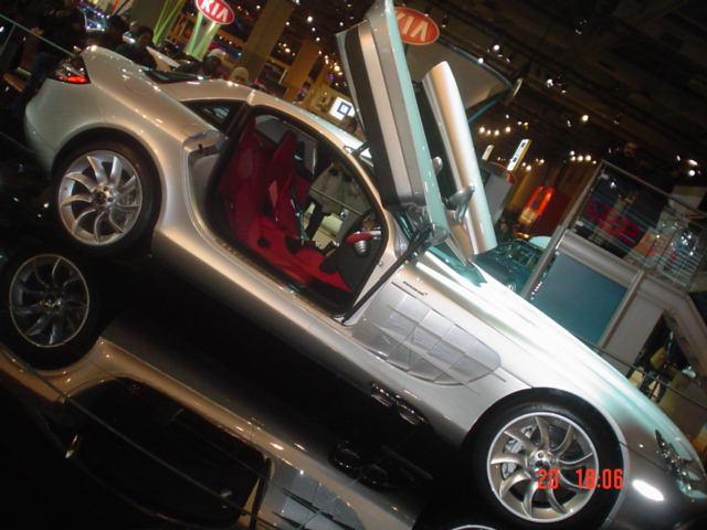 Silver Mercedes SLR McLaren with red interior and swing-up door at auto show