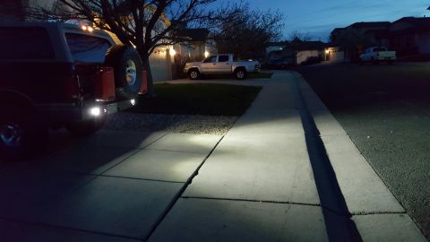 1996 Ford Bronco - The rear of a dark red SUV with a spare tire mounted on the back is parked on a concrete driveway at dusk. The vehicle has aftermarket ligh…
