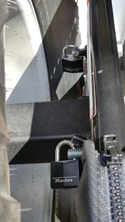 1996 Ford Bronco - Two black Master brand padlocks secure a metal component to a vehicle's frame. One padlock is visible in the foreground, and another is sli…