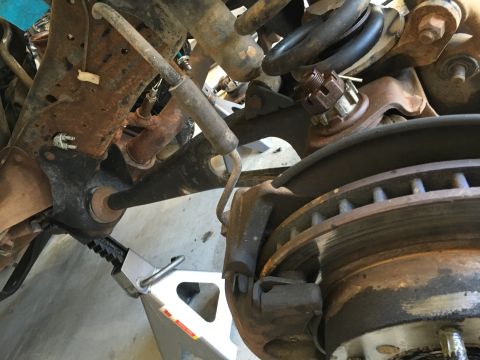 1987 Ford Bronco - This is a close-up view of the front suspension and braking system of a vehicle, likely undergoing maintenance. The components, including t…