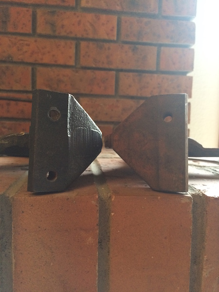 1981 Ford Bronco - Two metal brackets with holes are shown against a brick background. The bracket on the left is dark and appears to be made of cast iron, wh…