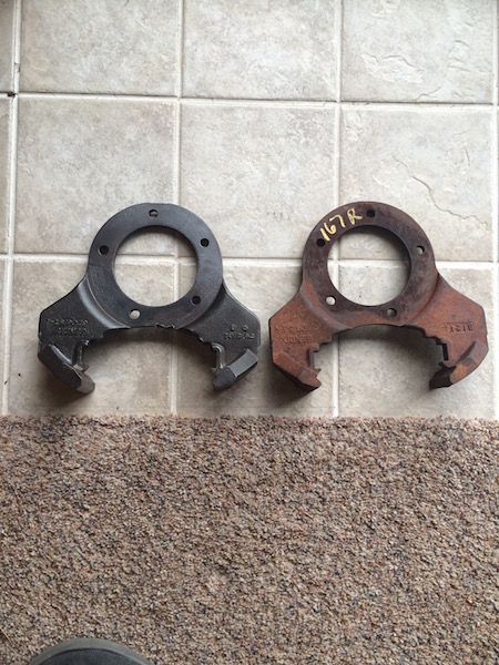 1981 Ford Bronco - Two metal parts are laid out on a tiled floor and carpet. The part on the left is black and appears to have some text and numbers stamped o…