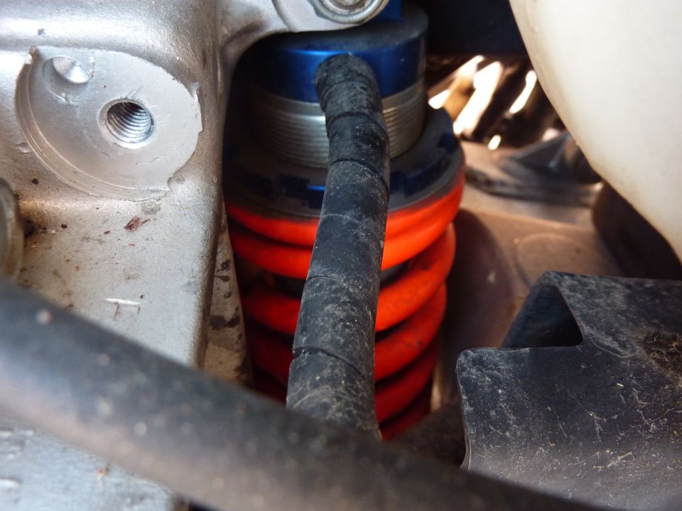 Motorcycle rear shock absorber with orange spring and black boot.