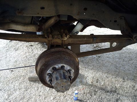 1996 Ford Bronco - Close-up of a vehicle's rear axle and suspension components, including a drum brake and shock absorber.