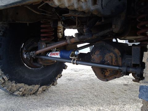1996 Ford Bronco - The underside of an off-road vehicle shows its suspension and steering components, including a Rancho steering stabilizer.