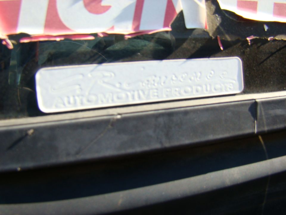 Close-up of a white sticker on a car window with "AUTOMOTIVE PRODUCTS" and an "R" logo.