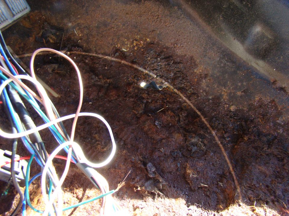 Heavily rusted metal surface with a tangle of colorful electrical wires.