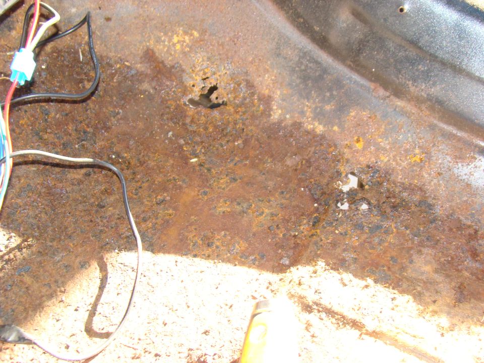 Rust and hole in vehicle floor pan with wiring.