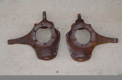 1974 Ford Bronco - A pair of heavily rusted steering knuckles are displayed on a concrete surface.