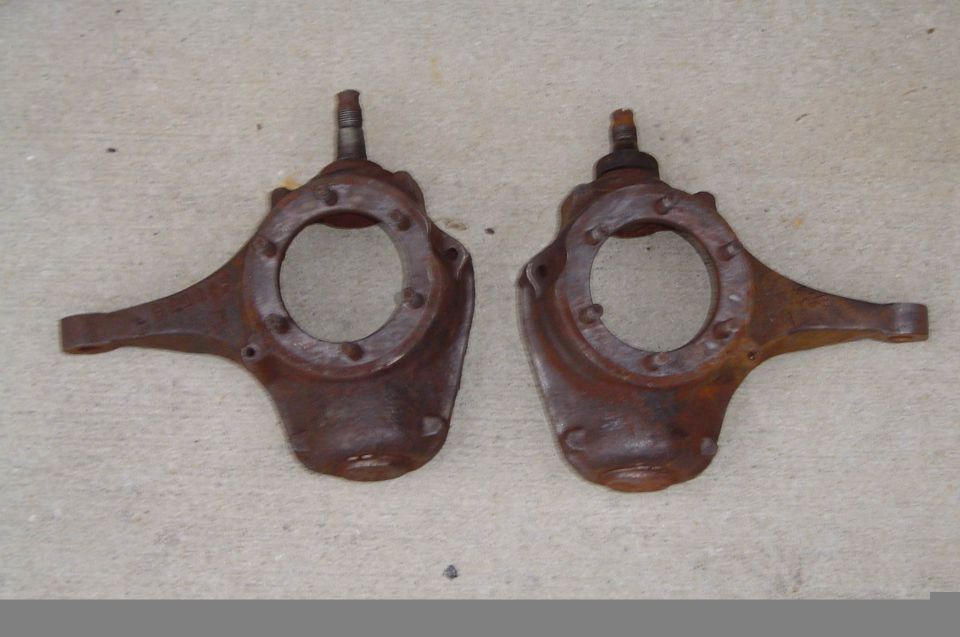 Pair of rusty cast steering knuckle spindles laid on concrete floor