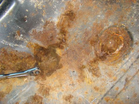 1981 Ford F-100 - A close-up view of heavily rusted metal, possibly the floor pan of a vehicle, with a socket wrench resting on the surface. The rust is exte…