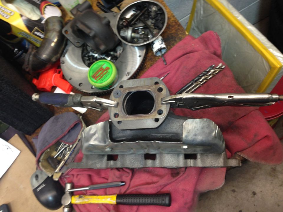 Turbocharger exhaust manifold with tools on a red cloth.