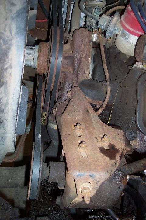 1973 Ford F-250 - This close-up image shows the heavily rusted engine components of a vintage Ford F-250, including the alternator bracket, belts, and pulley…