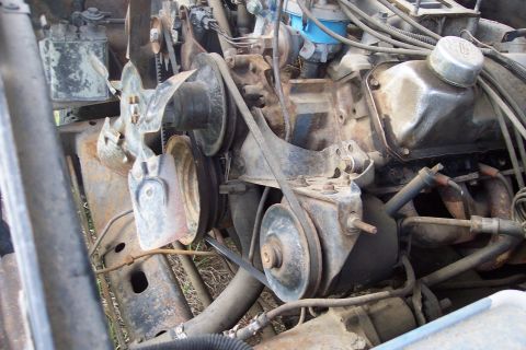 1973 Ford F-250 - A close-up view of a heavily rusted engine bay, focusing on the belts and pulleys of a V8 engine. The engine appears to be from an older Fo…