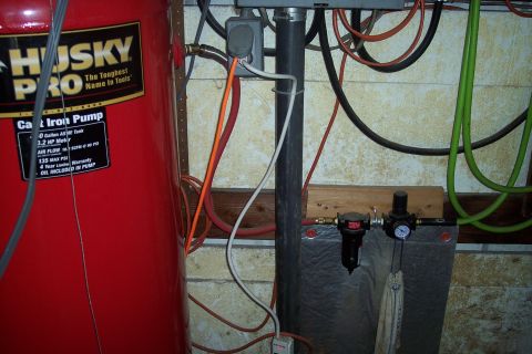 1990 Ford Bronco - A red Husky Pro air compressor tank is shown with various air hoses and electrical cords connected to it. A black pipe and a pressure regul…