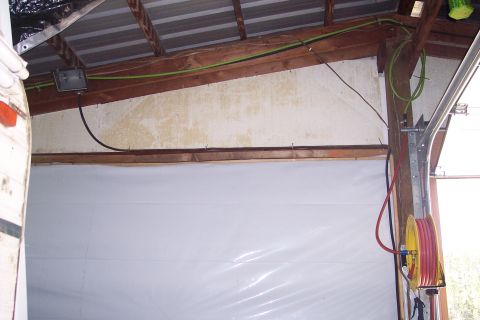 1990 Ford Bronco - This image shows the interior of a garage or workshop with exposed wooden beams and a corrugated metal roof. Electrical wiring, a white pla…