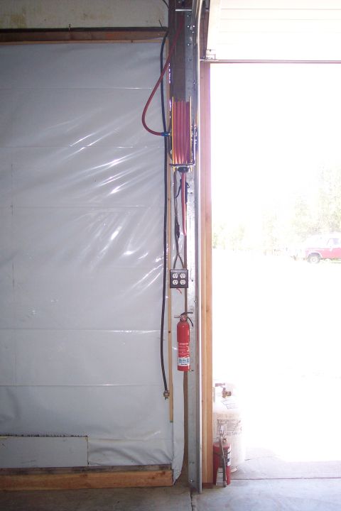 1990 Ford Bronco - A fire extinguisher is mounted on a wall next to a garage door opening. Electrical outlets and a coiled hose reel are also visible on the w…