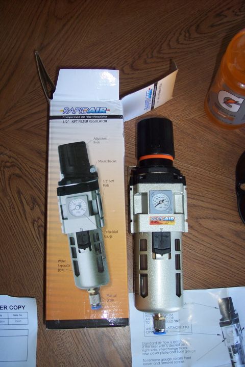 1990 Ford Bronco - A Rapidair compressed air filter regulator is shown next to its packaging. The regulator has a silver body, a black adjustment knob, and an…