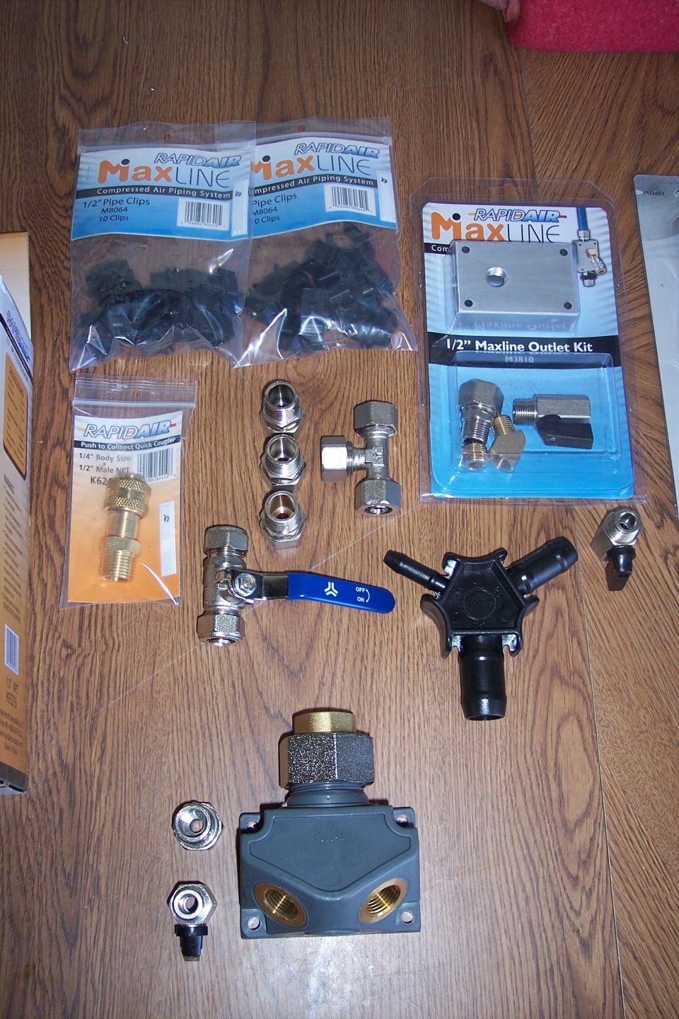 RapidAir Maxline compressed air piping system components and fittings on a wooden floor.