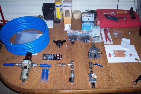 1990 Ford Bronco - A collection of pneumatic fittings, tubing, and tools are laid out on a wooden table. The items include a large coil of blue tubing, an air…