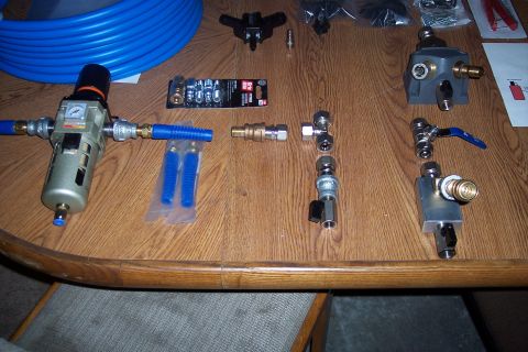 1990 Ford Bronco - A collection of air compressor fittings, regulators, and tubing are laid out on a wooden table.