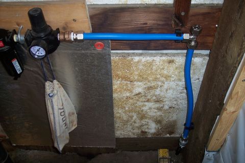 1990 Ford Bronco - A close-up view of an air compressor regulator with a gauge and a blue pneumatic line connected to it. A small cloth bag hangs from the reg…