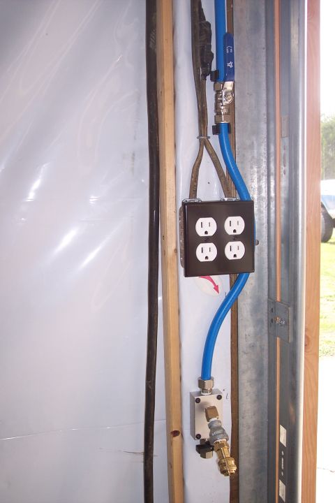 1990 Ford Bronco - A close-up view of electrical outlets and blue pneumatic tubing mounted on a wall, with wooden and metal framing visible.