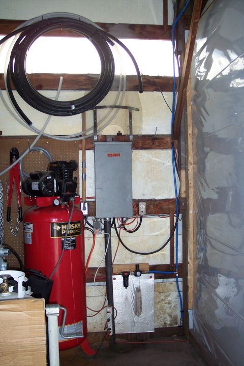 1990 Ford Bronco - A red air compressor with a Husky Pro label is connected to a 220 volt electrical box. Various hoses and electrical wires are visible in th…