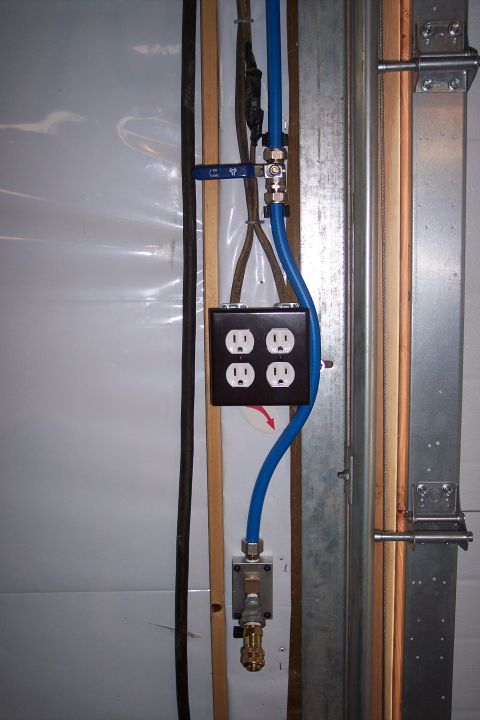1990 Ford Bronco - A close-up view shows a blue pneumatic line connected to a brass fitting and valve, running alongside electrical outlets and cables.