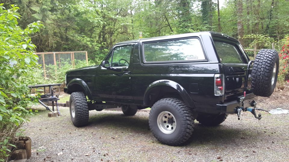 Black 1995 Ford Bronco with off-road tires and rear spare tire, parked outdoors.