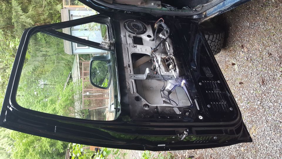Interior of a black vehicle door with panel removed, showing speaker and wiring.