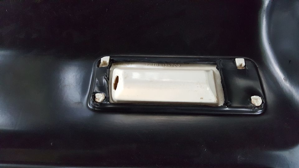 White plastic part with text F2TB-15K705 mounted on black surface