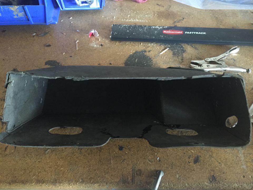 Black hollow object with cutouts on a workbench with tools.