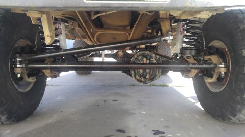 1991 Ford Bronco - The underside of a lifted 1991 Ford Bronco shows a modified suspension system with aftermarket shocks and springs, a camouflage-covered dif…