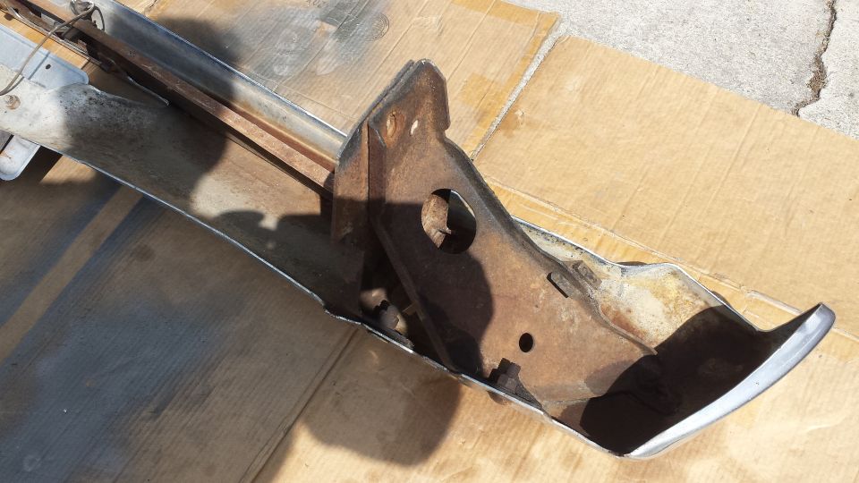 Rusty bumper assembly with chrome trim on cardboard