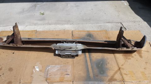 1976 Ford Ranchero - A chrome bumper with rusted metal brackets is laid out on cardboard boxes. The bumper appears to be from an older model pickup truck or car.