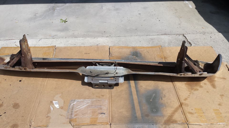 Chrome bumper with rusted brackets on cardboard