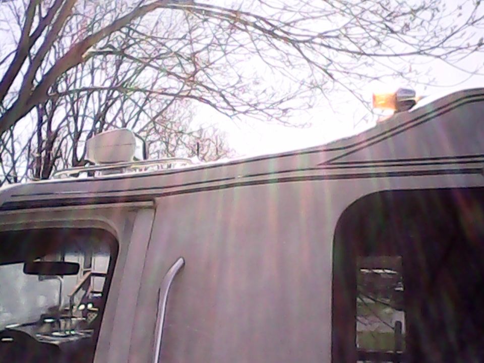 Side view of a van with a roof rack, white pod, and amber warning light.