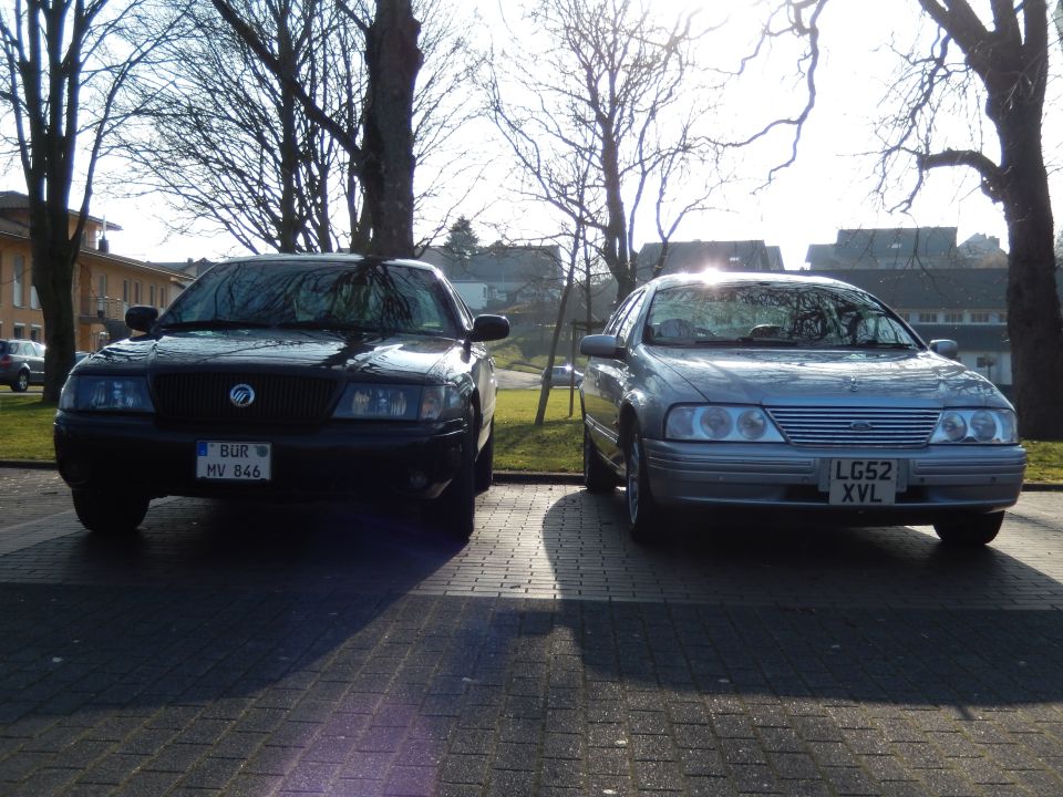 Two sedans, one black and one silver, parked on a paved lot.