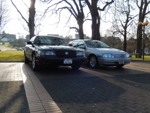 1999 Ford Fairlane - Two sedans are parked on a paved area with trees in the background. The sedan in the foreground is black and has a license plate that reads…