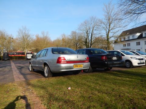 1999 Ford Fairlane - A silver 1999 Ford Fairlane sedan is parked on a paved lot next to a black sedan and two white cars. The car has a license plate that reads…
