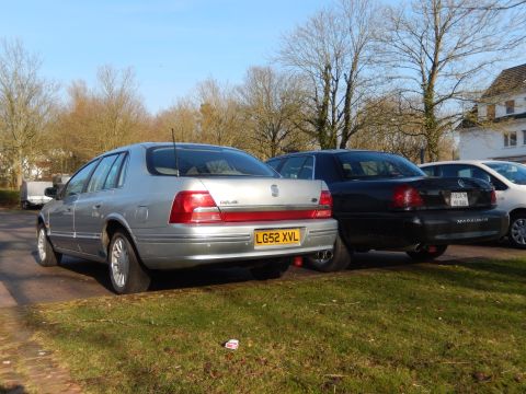 1999 Ford Fairlane - A silver 1999 Ford Fairlane sedan is parked on a grassy area next to a black Ford Marauder. The silver sedan has a yellow license plate tha…